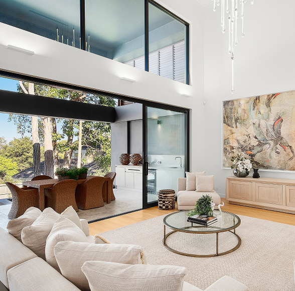 Cream living area with dramatic sheets of glass opening onto an outdoor dining area.
