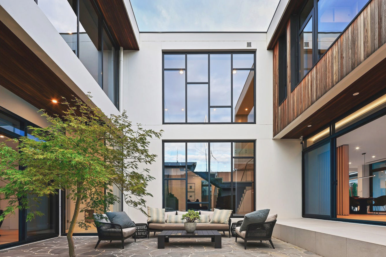 Courtyard with seating area of a modern building softened with a maple tree.