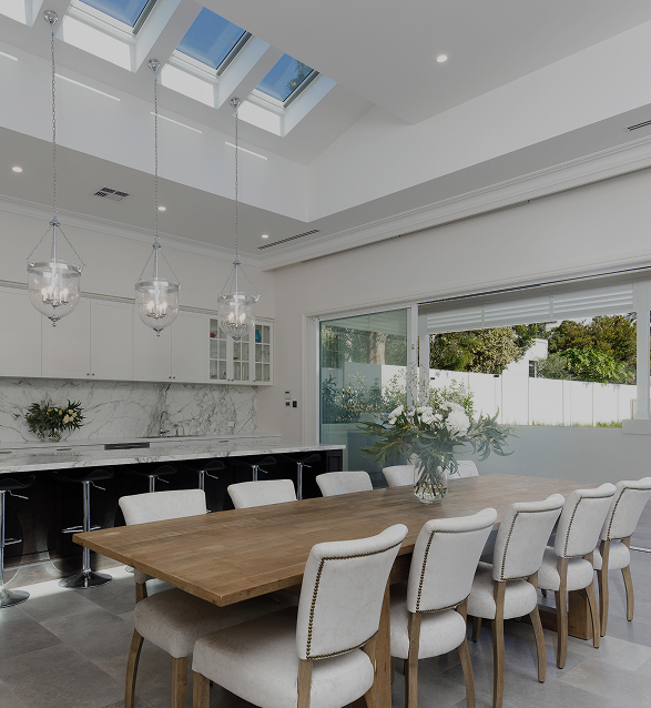 Expansive dining table with 10 chairs, with high ceilings and sky lights above