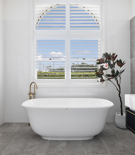 Standalone oval tub under arched windows