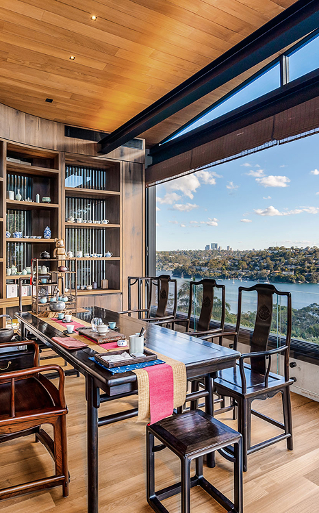Asian tea setting table surrounded by ultra modern architectural, softened with wooden panels, opening onto a river vista of Sydney CBD