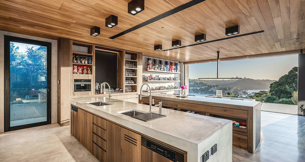 Ultra modern kitchen with polished concrete benchtops, softened with wooden panels on the ceiling and cupboards; looking out onto a floor-to-ceiling water view