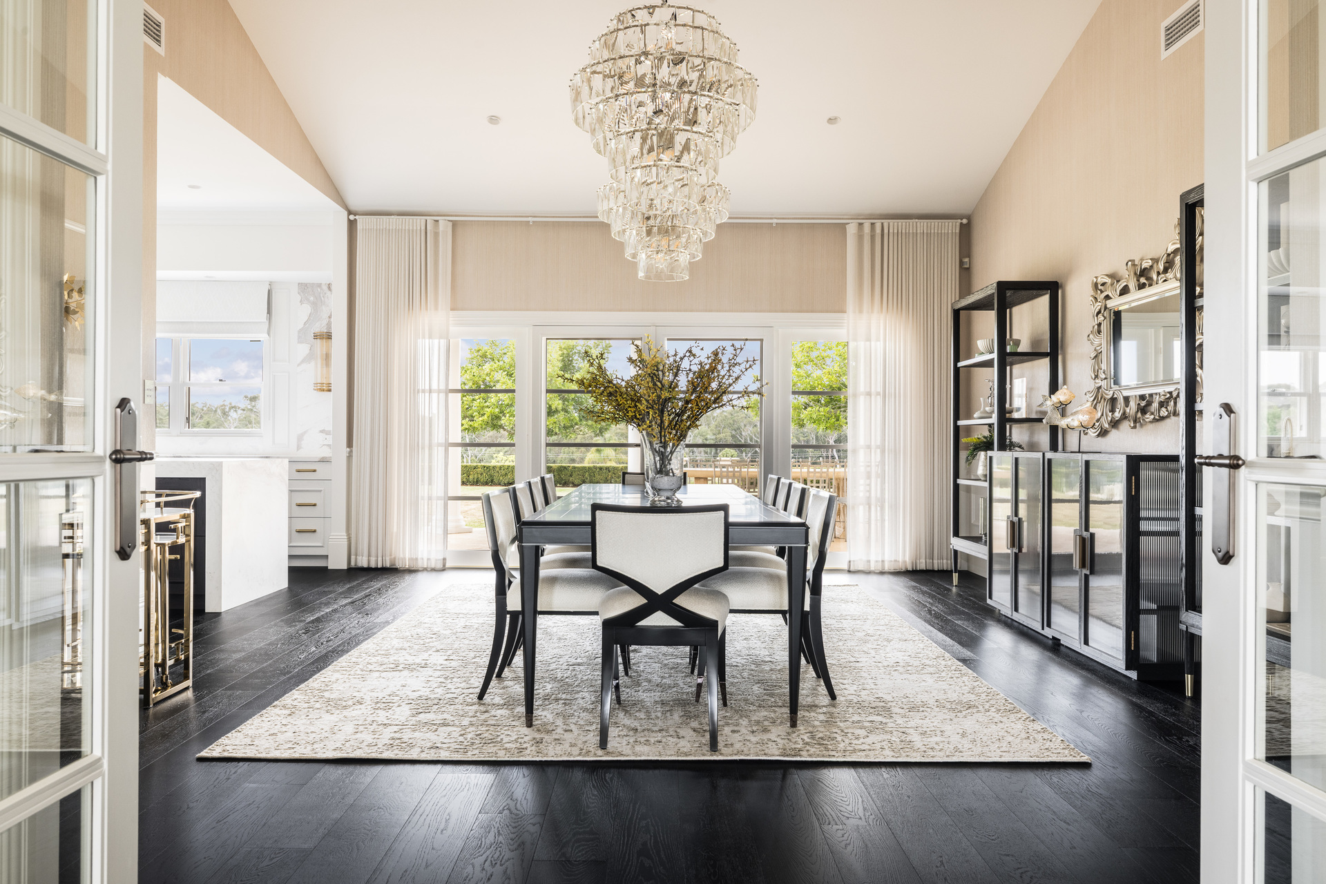 Refined, light-filled dining room, with a tall chandelier, cream with copper and charcoal accents.