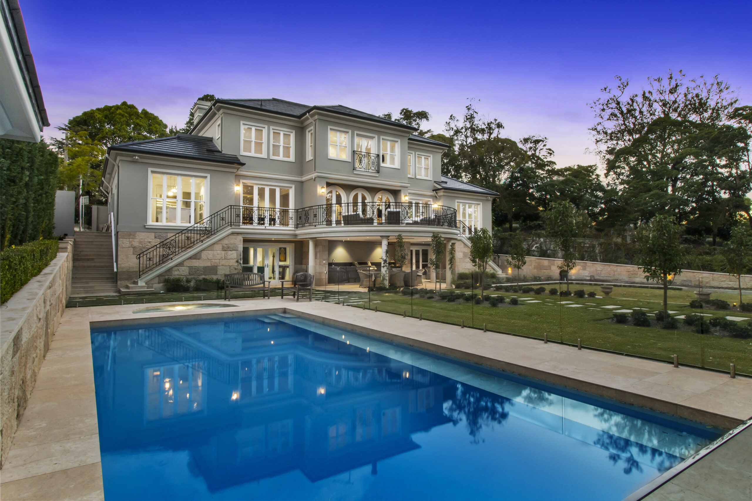 Pymble home in Provincial Style â€“ blue pool closeup with a grand, stately, provincial-style home rising up in the background