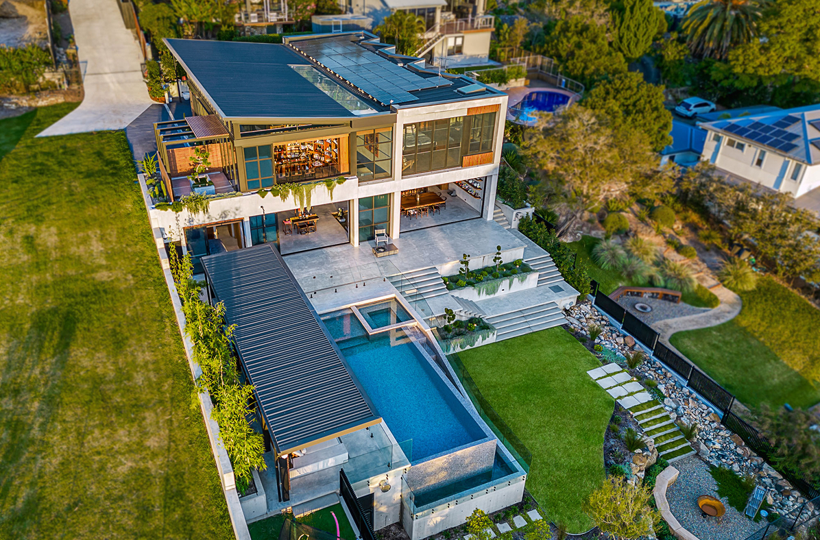 Drone view of ultra modern home; featuring pool, concrete walls and sandstone pavers