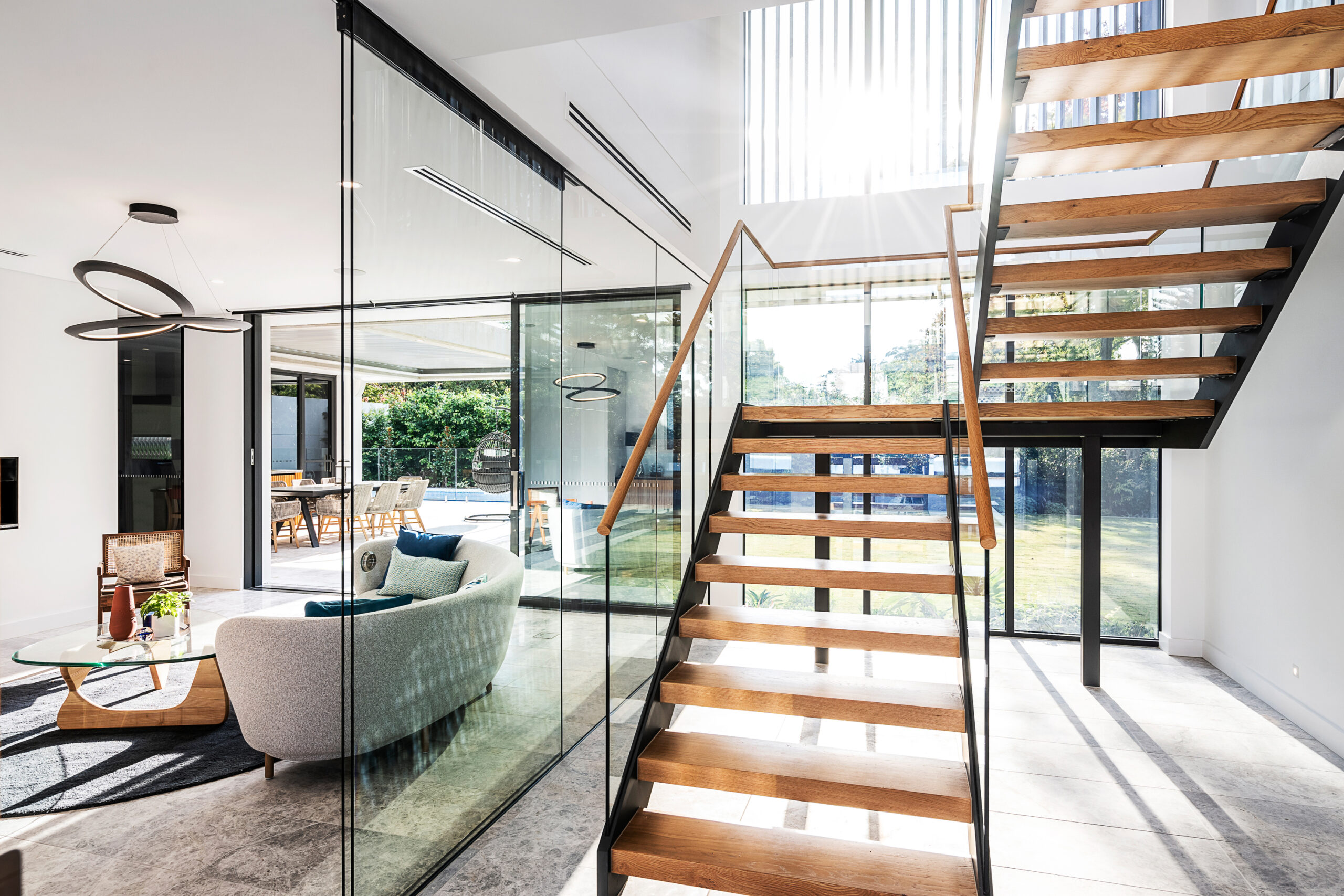 Ultra modern, floating wooden tread staircases surrounded with floor to ceiling glass, flooding the space with light.