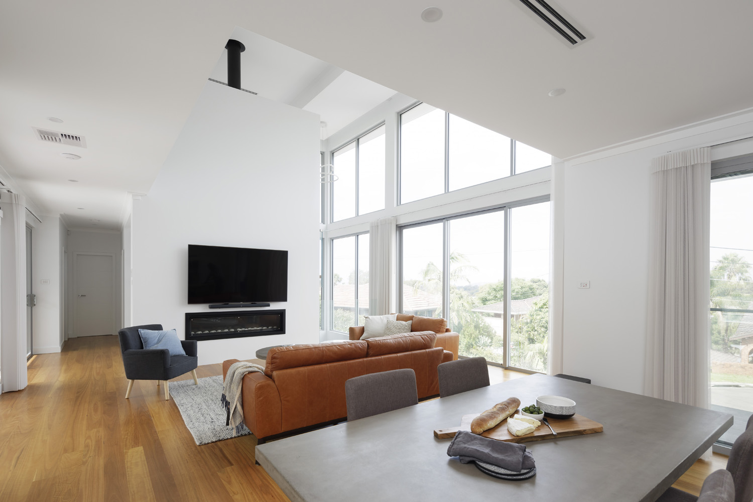 Brookvale Modern: View from dining to living area, with tall windows and ceiling
