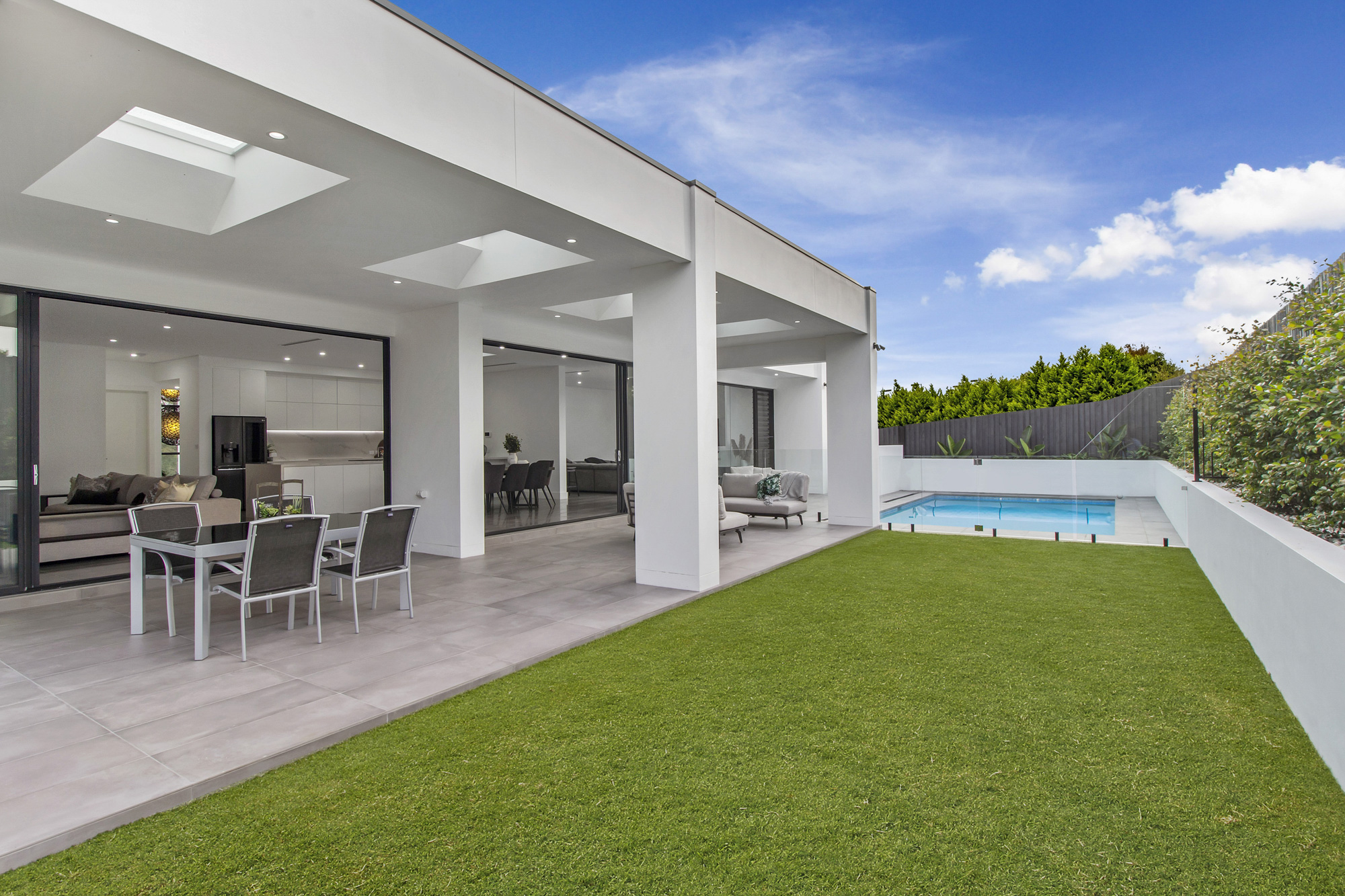 Glenhaven Modern Contemporary: backyard with outdoor dining and living area next to pool and green