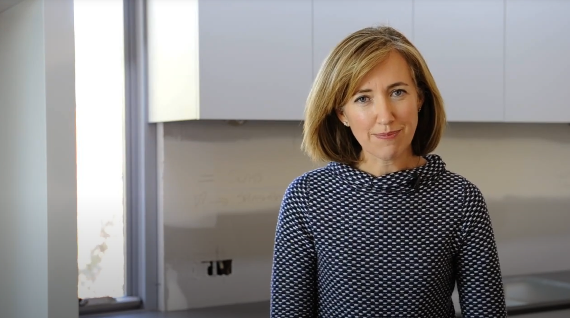Well presented woman talking to the camera while standing in a kitchen